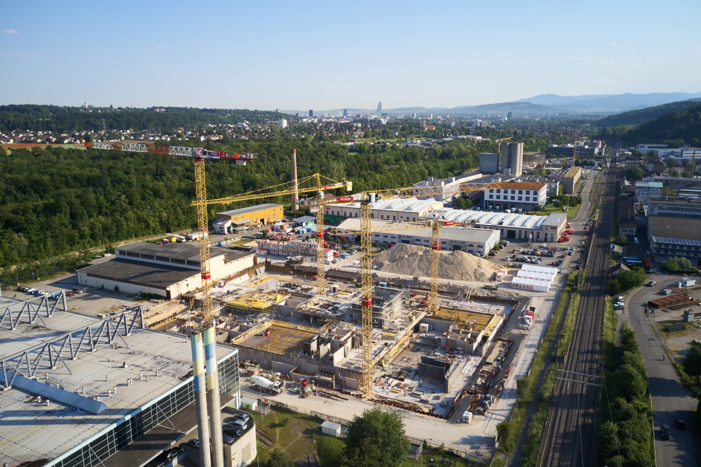 Photos pour ce dossier presse, Vue aérienne du chantier du centre-ville de Bâle à partir du 5 juin 2019 avec le viaduc du Sundgauer en direction de la ville de Bâle. Aux portes de la ville universitaire de Bâle, un centre de compétences pour l’industrie 4.0 est en construction. © Copyright Bela Böke, arbel gmbh| Digitale Medienmappe «Première pierre de l’uptownBasel: un «saut quantique» pour l’industrie», uptownBasel
